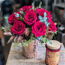 Bouquet of hot pink roses in a decorative vase beside a candle jar