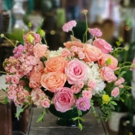 Pink and peach rose arrangement in a dark vase
