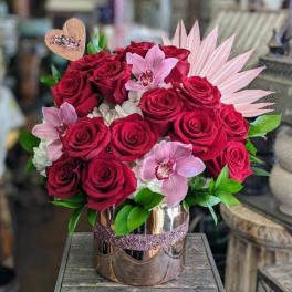 Bouquet of red roses and pink orchids in a metallic vase