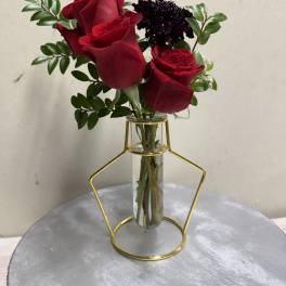 Red roses in a clear glass vase with greenery