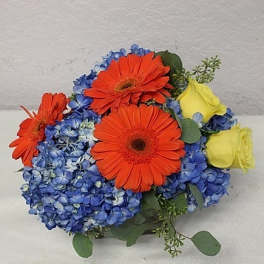 Bouquet of orange gerbera daisies, blue hydrangeas, and yellow roses