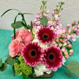 Pink roses and magenta gerbera daisies in a low arrangement