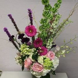 Tall mixed bouquet in a glass vase with pink and purple flowers