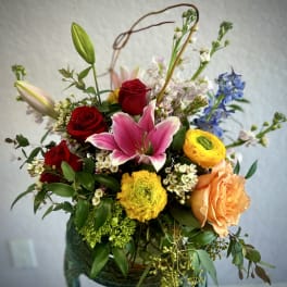 Mixed bouquet with red roses, pink lily, and yellow blooms in a vase