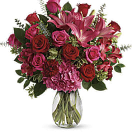 Bouquet of red and pink roses with lilies in a clear glass vase