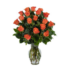 Tall arrangement of orange roses with lush foliage in a clear glass vase