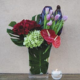 Mixed floral arrangement in a clear vase with red and pink blooms