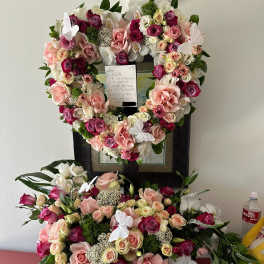 Heart-shaped floral tribute with pink and white roses on a stand
