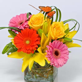 Bright mixed bouquet in a square glass vase with butterflies