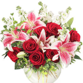 Bouquet of red roses and pink lilies in a clear glass vase