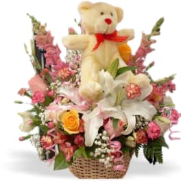 Teddy bear in a basket arrangement with lilies and pink flowers