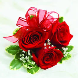 Three red roses with a red ribbon bow and small white filler flowers