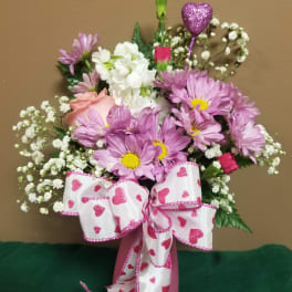 Pink and white bouquet in a pink vase with a heart ribbon