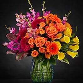 Colorful bouquet of roses, gerbera daisies, and calla lilies in a glass vase