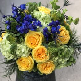 Yellow roses with blue flowers in a dark vase