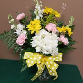 Bouquet of white and pink flowers with yellow daisies in a glass vase