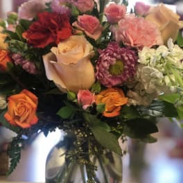 Mixed bouquet of roses, carnations, and chrysanthemums in a glass vase