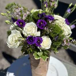 Bouquet of white roses and purple lisianthus in a wrapped vase
