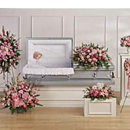 Funeral casket surrounded by pink floral sprays and wreaths