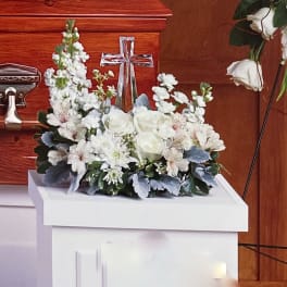 White floral arrangement with roses and a cross centerpiece