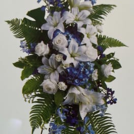 White lilies and blue flowers arranged on a standing easel