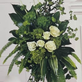 Tall white rose arrangement with lush green foliage on a stand