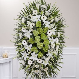 White funeral spray with lilies, daisies, and green anthurium on a stand