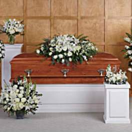 White funeral casket surrounded by white floral sprays and wreaths