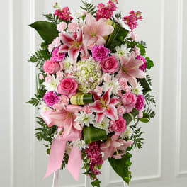 Pink and white floral standing spray with lilies, roses, and ribbon