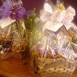 Two wrapped gift baskets with bows sit on a table.