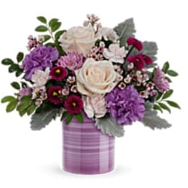 Bouquet of cream, purple, and pink flowers in a striped lavender vase