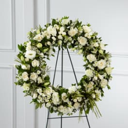 Large white floral wreath on a black stand