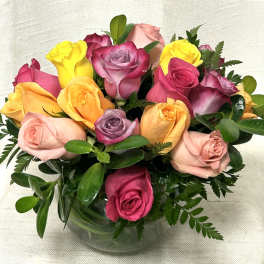 Low round arrangement of mixed-color roses in a clear glass bowl vase