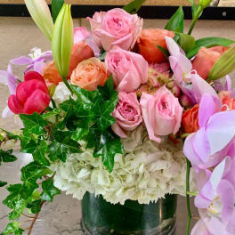 Mixed bouquet of pink and peach roses with white hydrangeas in a glass vase