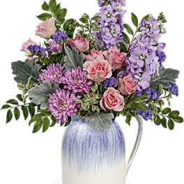 Lavender and pink mixed flower arrangement in a blue and white ceramic pitcher