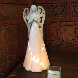 Ceramic angel figurine beside a small square candle holder