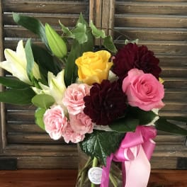Bouquet of pink and yellow roses with white lilies in a glass vase