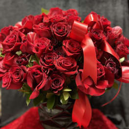 Bouquet of red roses with a red ribbon in a dark vase