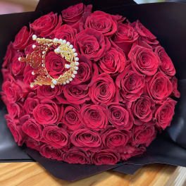 Bouquet of deep pink roses wrapped in black paper with a jeweled crown accent