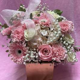 Pink and white flower arrangement in a square box with a sheer ribbon