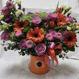 Bouquet of pink roses and orange gerbera daisies in an orange vase
