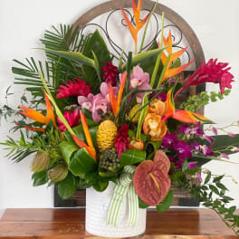 Tropical flower arrangement in a white vase with orange and pink blooms