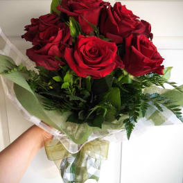 Bouquet of red roses wrapped in green and clear paper
