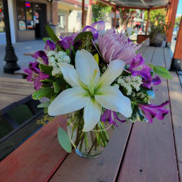 Bouquet of white lilies and purple flowers in a glass vase