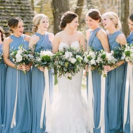 Bride and bridesmaids holding white and green bouquets outdoors