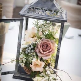 Lantern filled with pale roses and small white flowers
