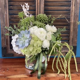 Mixed floral arrangement in a clear glass vase with white and green blooms