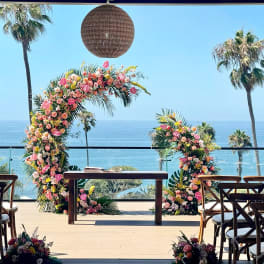 Floral wedding arch with pink and peach flowers overlooking the ocean