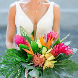 Bride holding a tropical bouquet with pink, orange, and yellow flowers