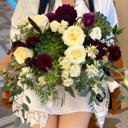 Wedding bouquet of cream and burgundy flowers with greenery